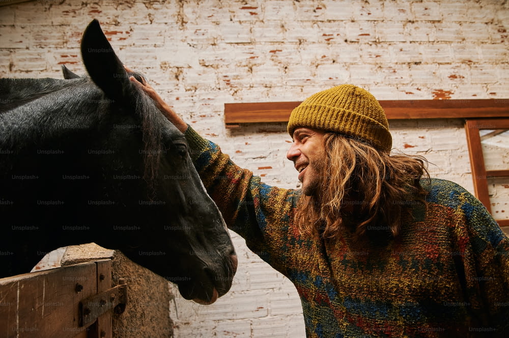 a man petting a horse next to a brick wall