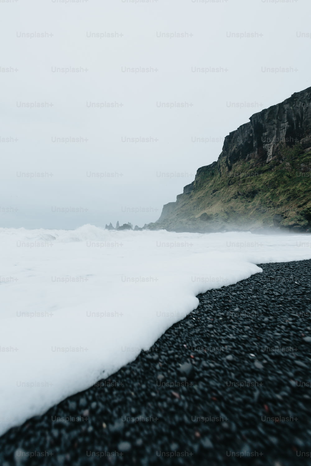 Ein schwarzer Strand mit einer Klippe im Hintergrund