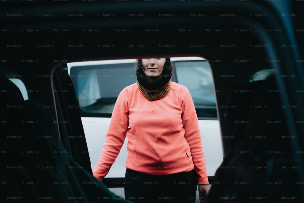 a woman in an orange shirt standing in front of a van