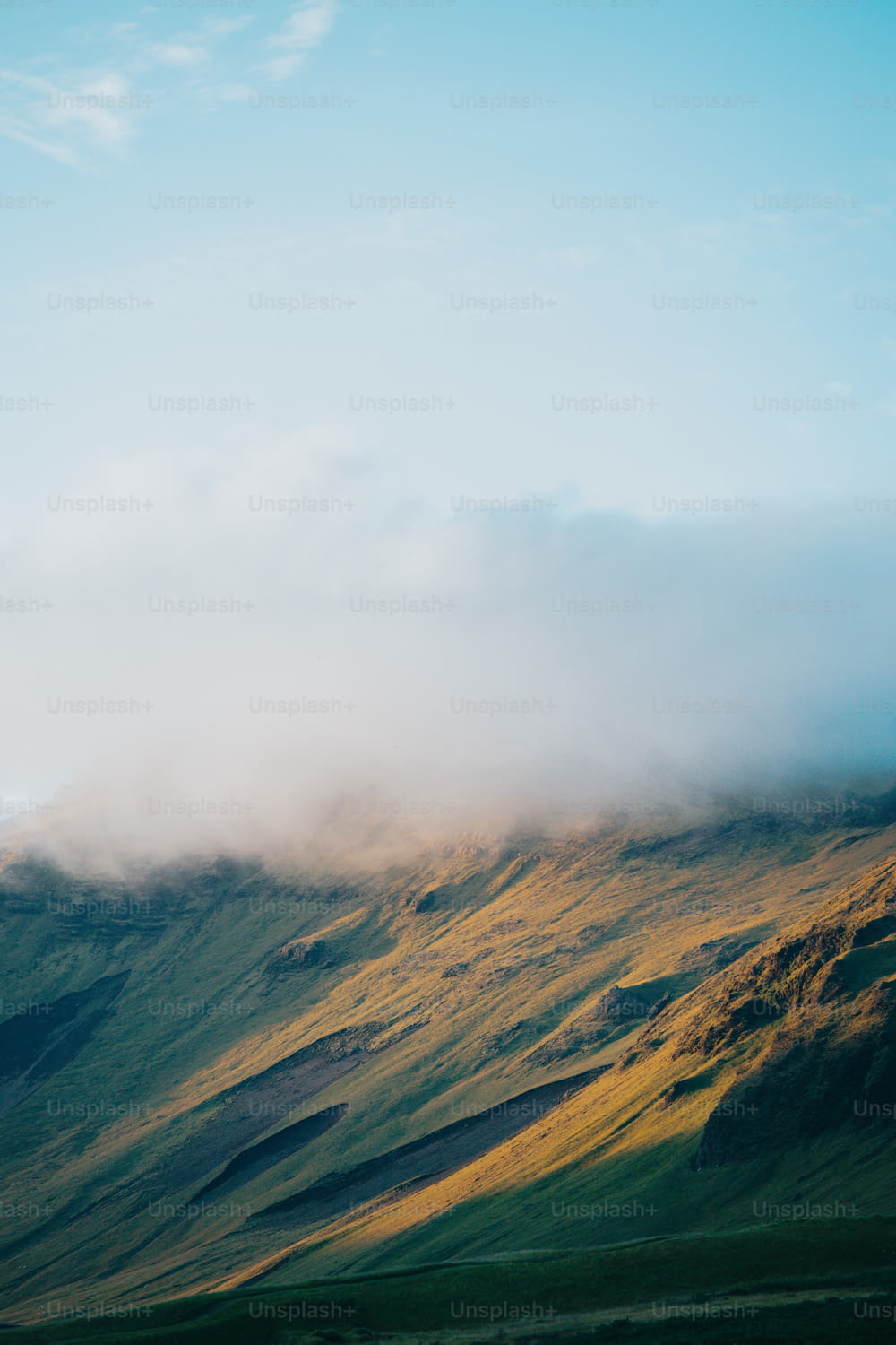 Una montaña cubierta de niebla y nubes en un día soleado
