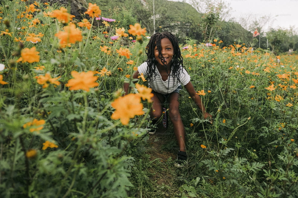 Una bambina inginocchiata in un campo di fiori