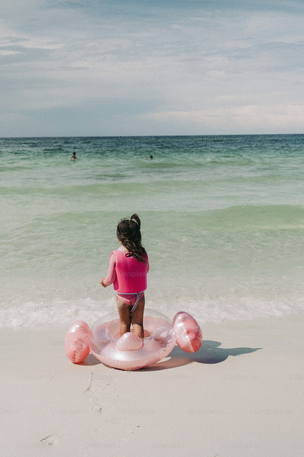 a little girl in a pink shirt standing on an inflatable float at the