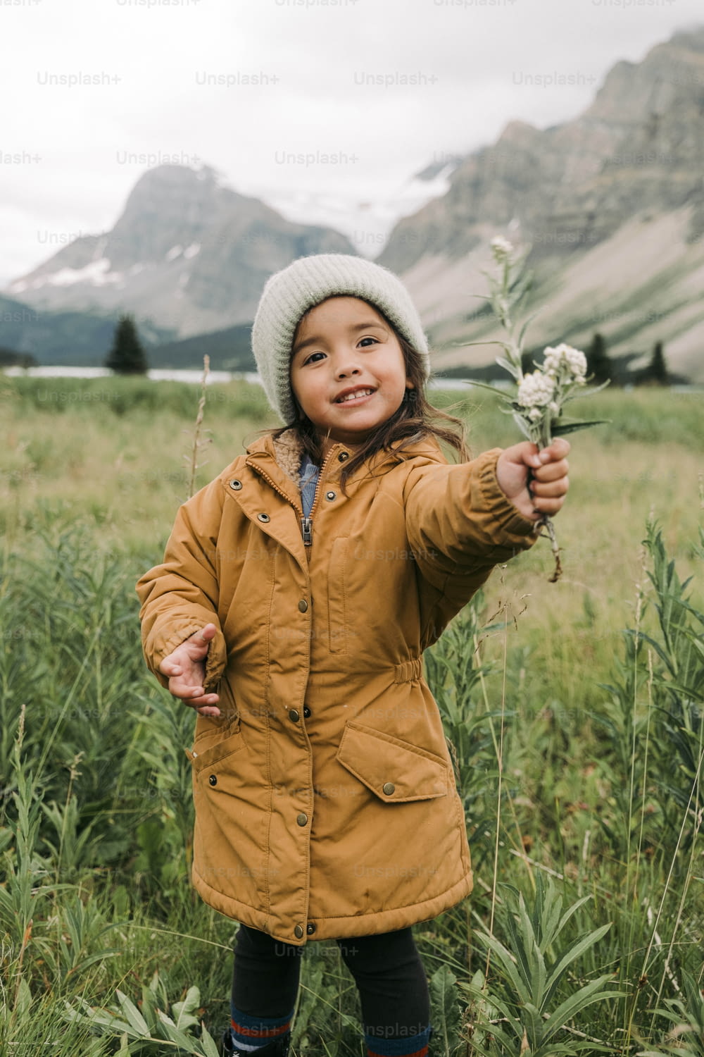 a little girl standing in a field holding a flower