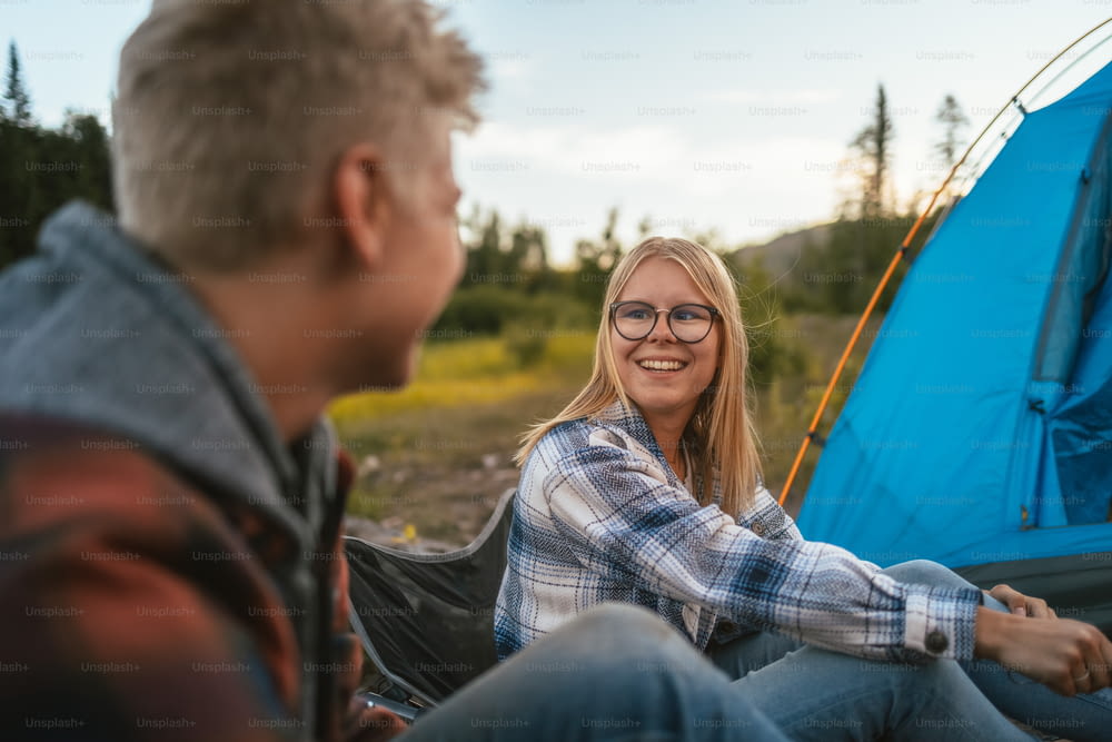 um homem e uma mulher sentados ao lado de uma tenda