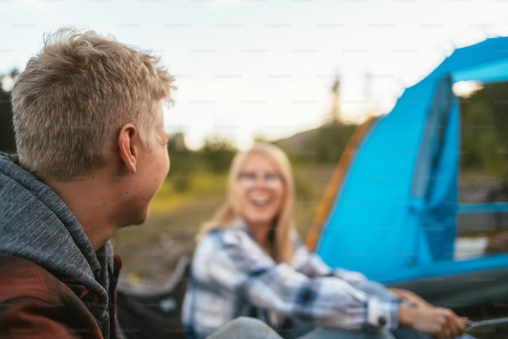 um homem e uma mulher sentados ao lado de uma tenda azul