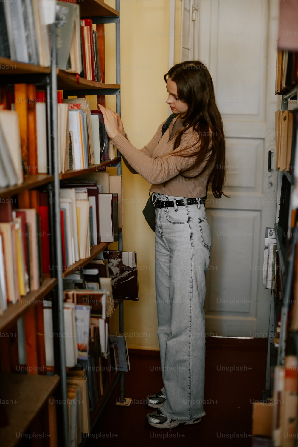 Une femme debout devant une étagère à livres