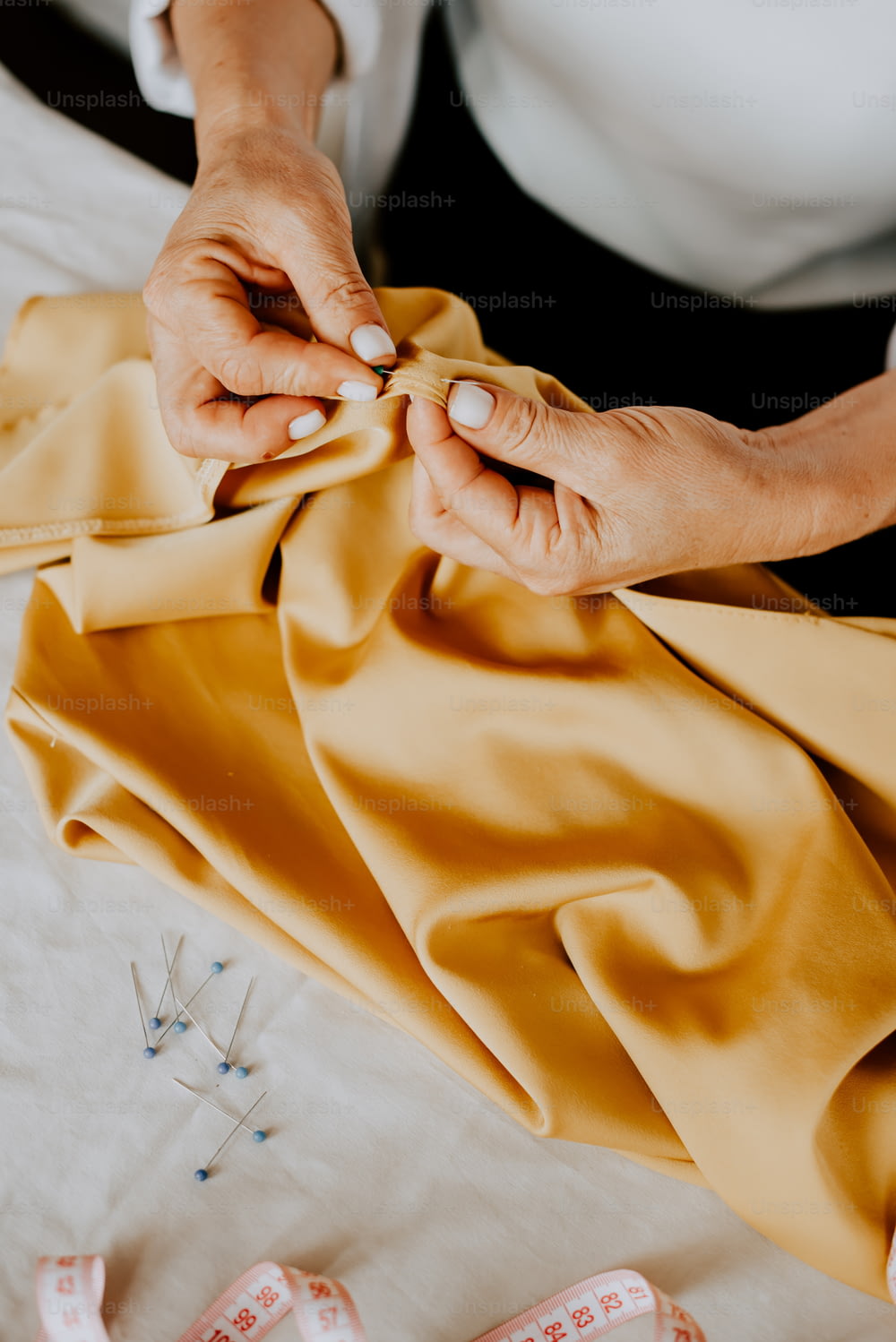a woman is sewing a yellow cloth on a sewing machine