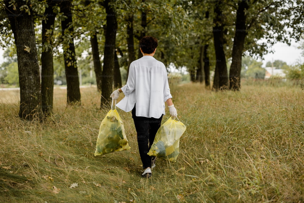 a woman walking through a field carrying two bags