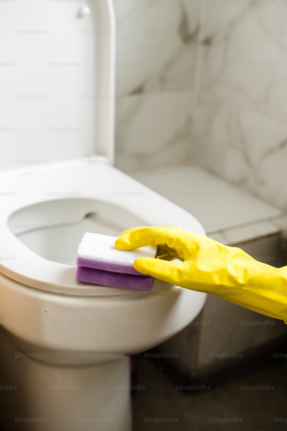 a person in yellow rubber gloves cleaning a toilet