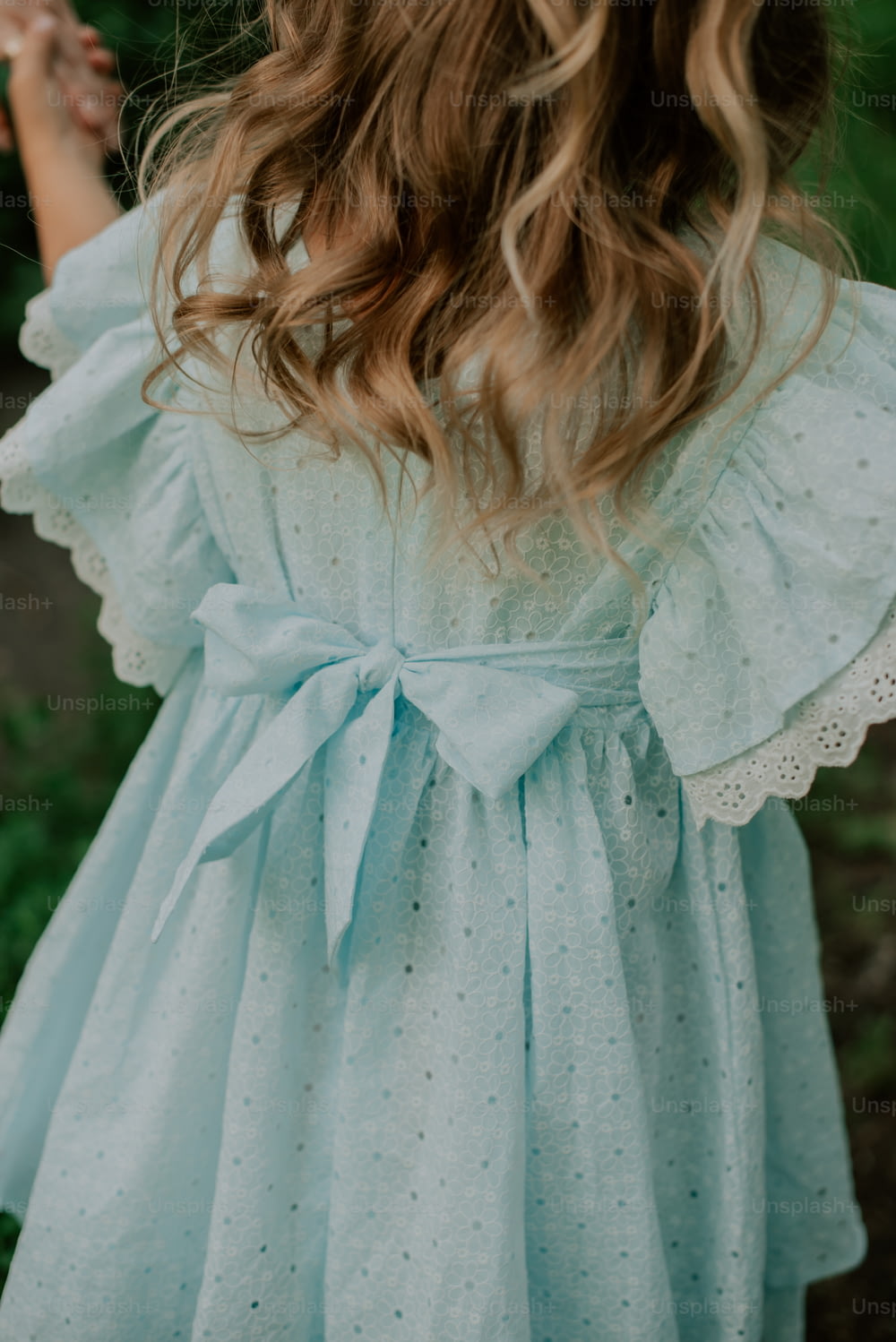 uma menina usando um vestido azul com um laço
