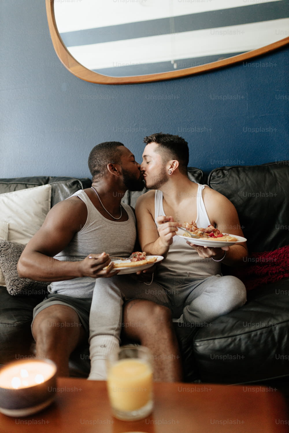 ソファに座ってピザを食べる2人の男性