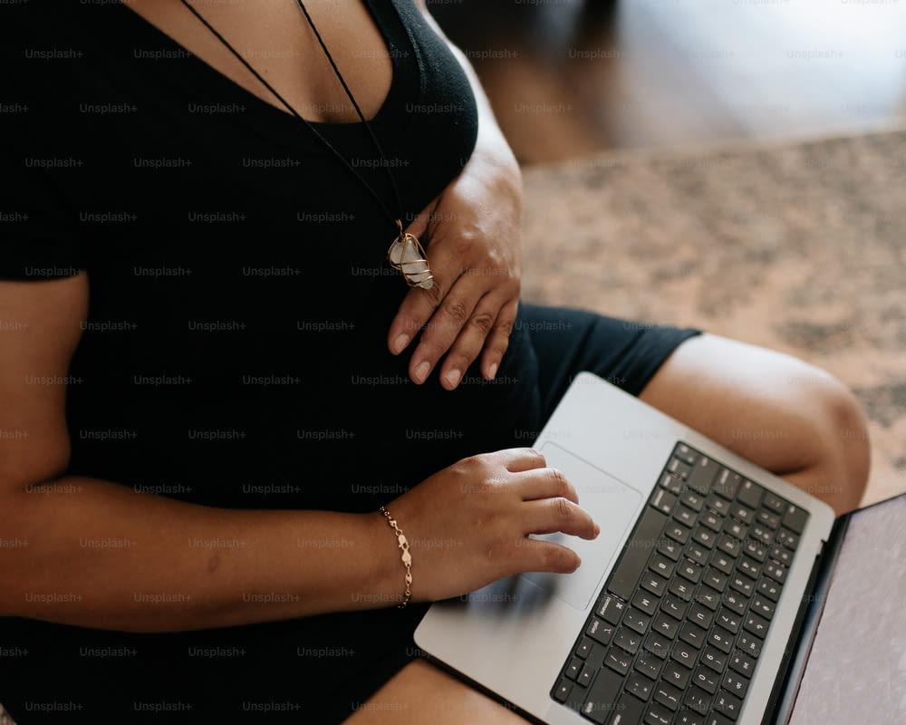 a pregnant woman sitting on the floor using a laptop computer