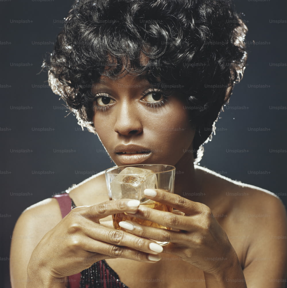 Una mujer sosteniendo un vaso de líquido en sus manos