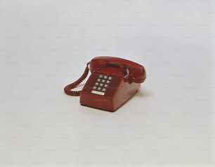 Un teléfono rojo sentado encima de una mesa blanca