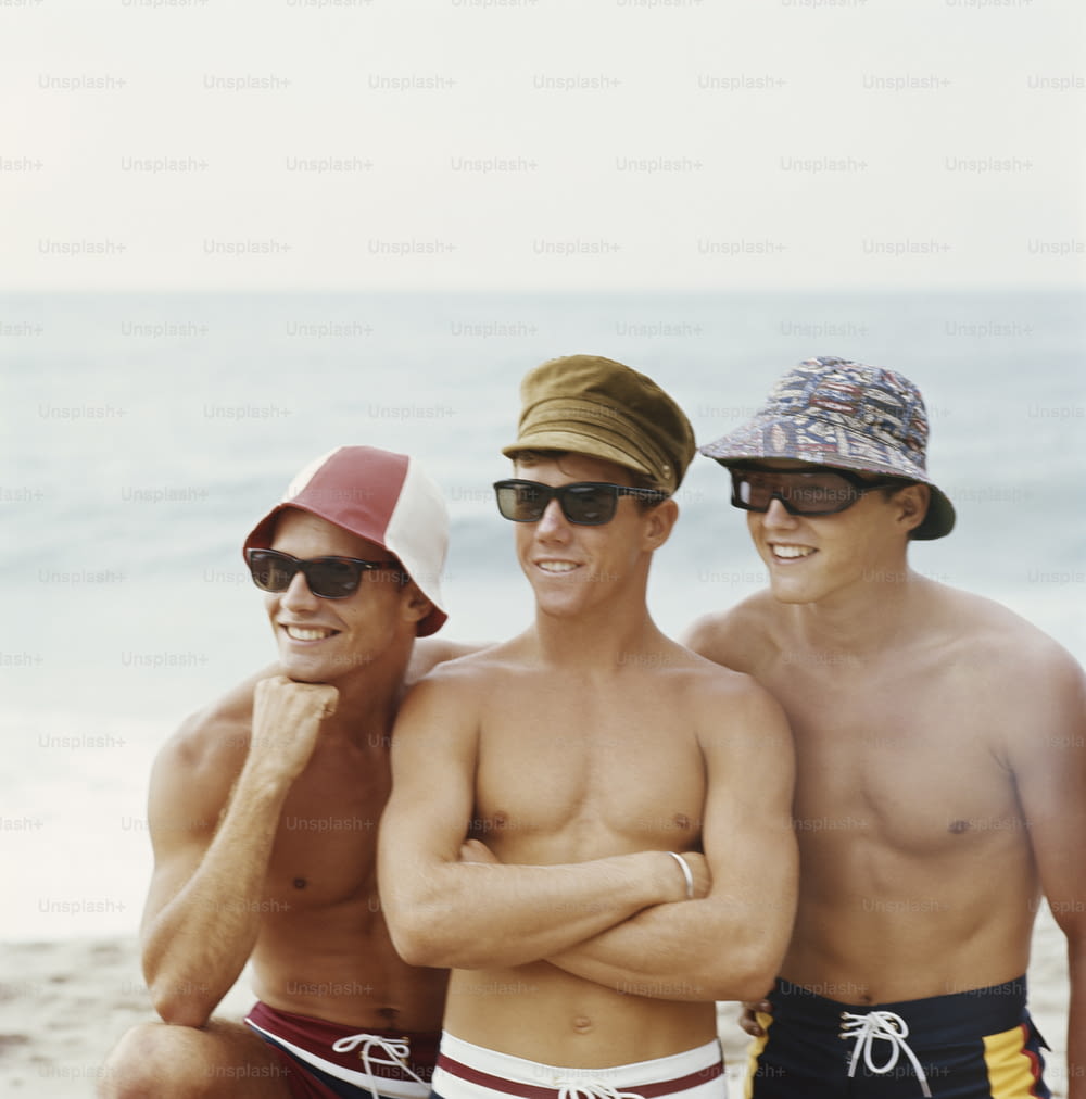 a group of three men standing next to each other on a beach