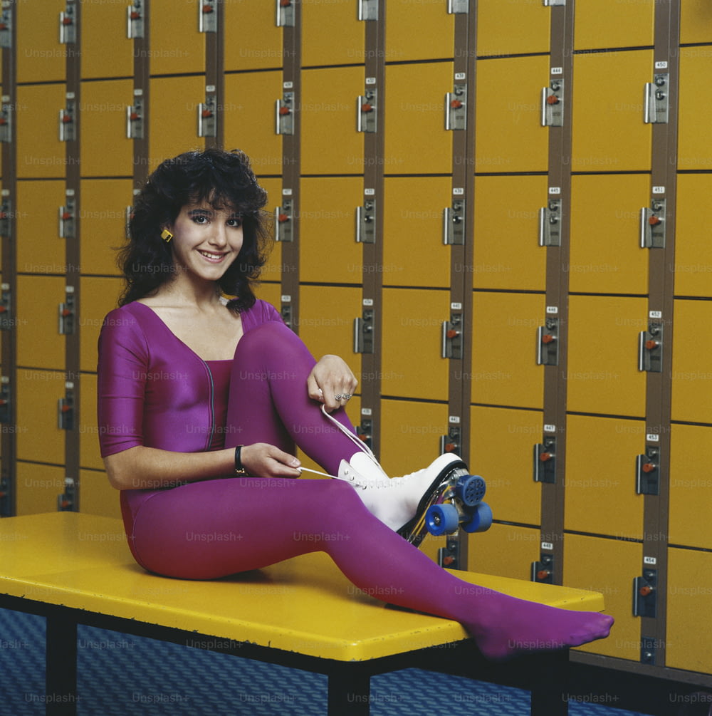 a woman sitting on a bench in front of lockers
