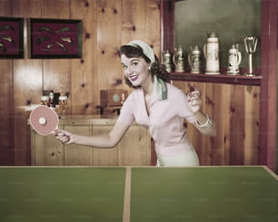 Una mujer sosteniendo una paleta de ping pong en una habitación