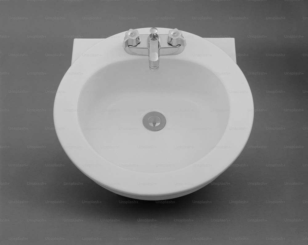 ein weißes Porzellanwaschbecken mit einem verchromten Wasserhahn