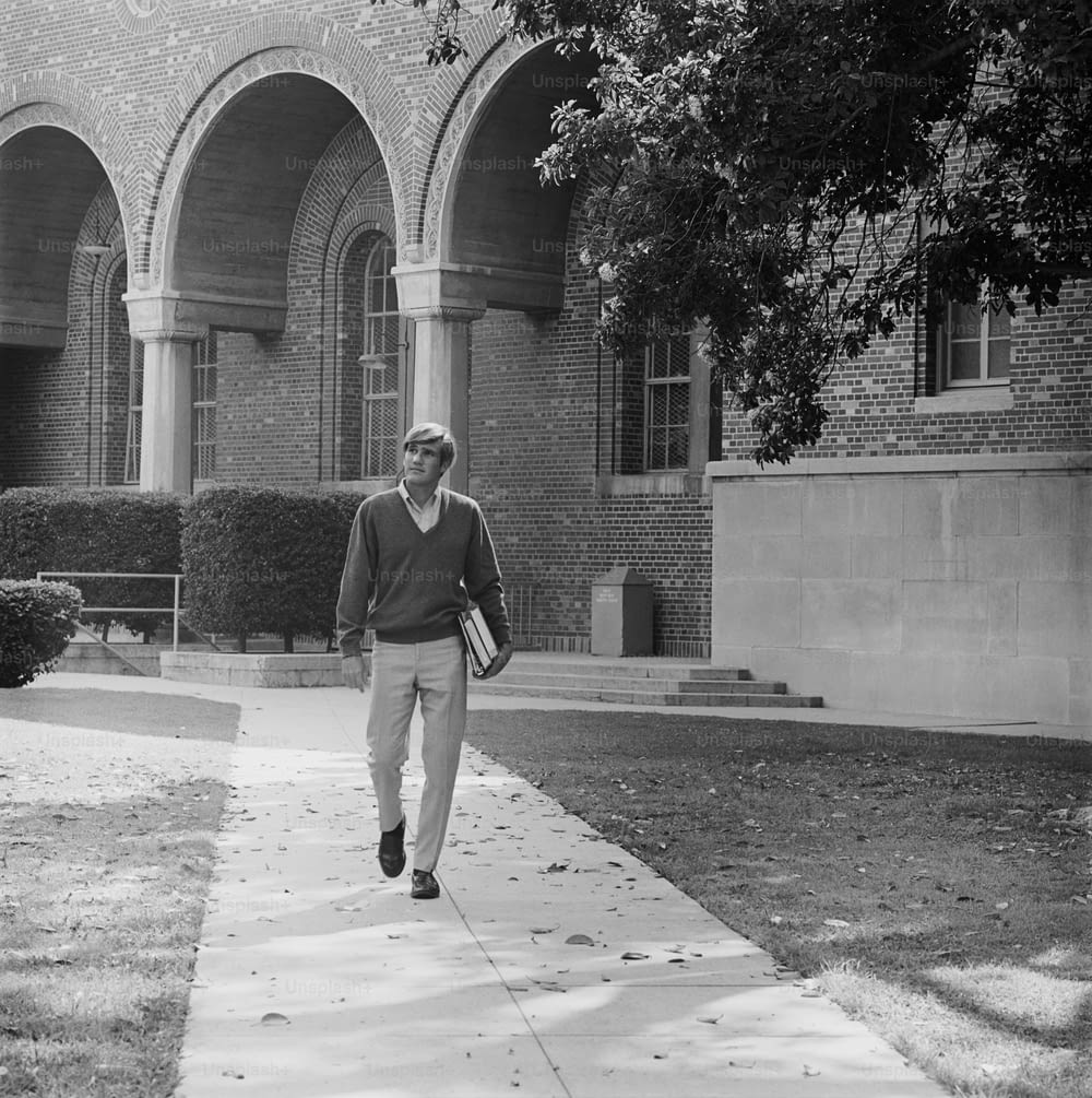 a man walking down a sidewalk in front of a building