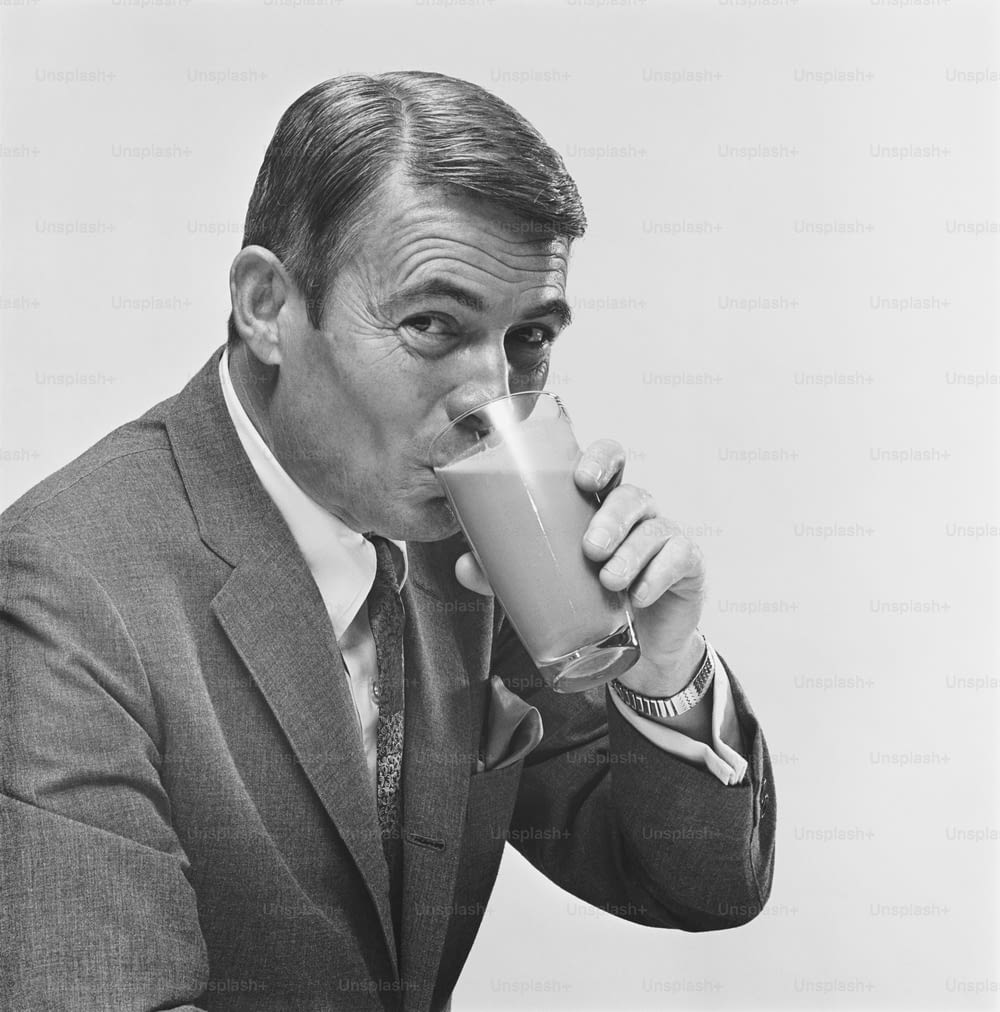 a black and white photo of a man drinking a drink