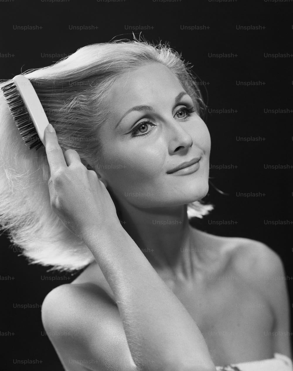 a black and white photo of a woman brushing her hair