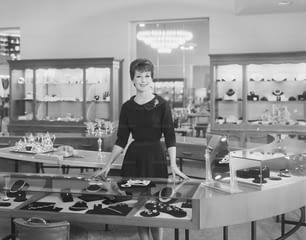 Una donna in piedi davanti a un tavolo pieno di gioielli