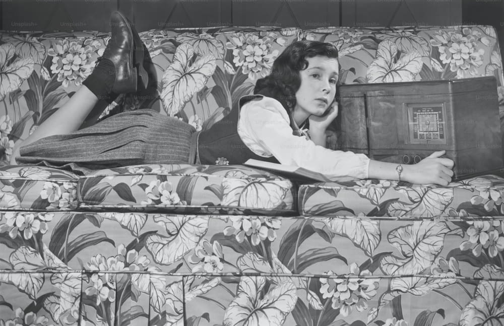 Una mujer acostada encima de un sofá floral