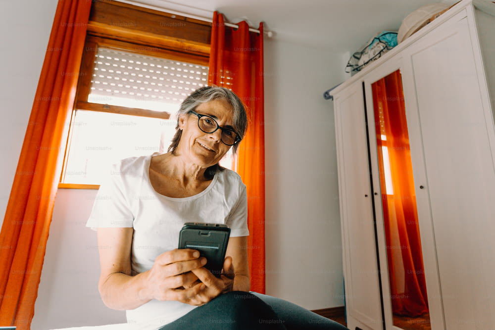 a woman sitting on a bed looking at her cell phone