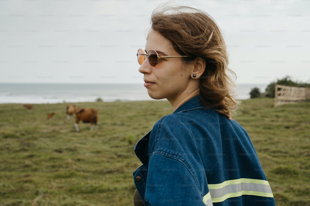 Una mujer parada en un campo con vacas en el fondo