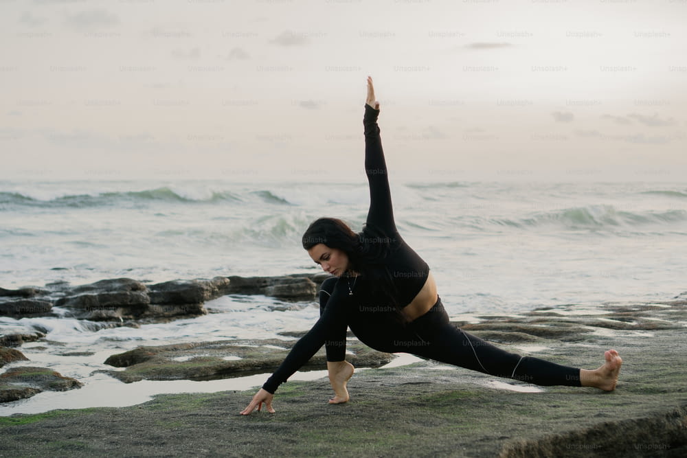 a woman doing a yoga pose on the beach