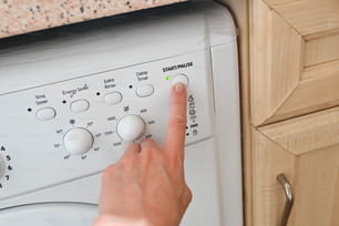 une personne appuyant sur des boutons sur une machine à laver