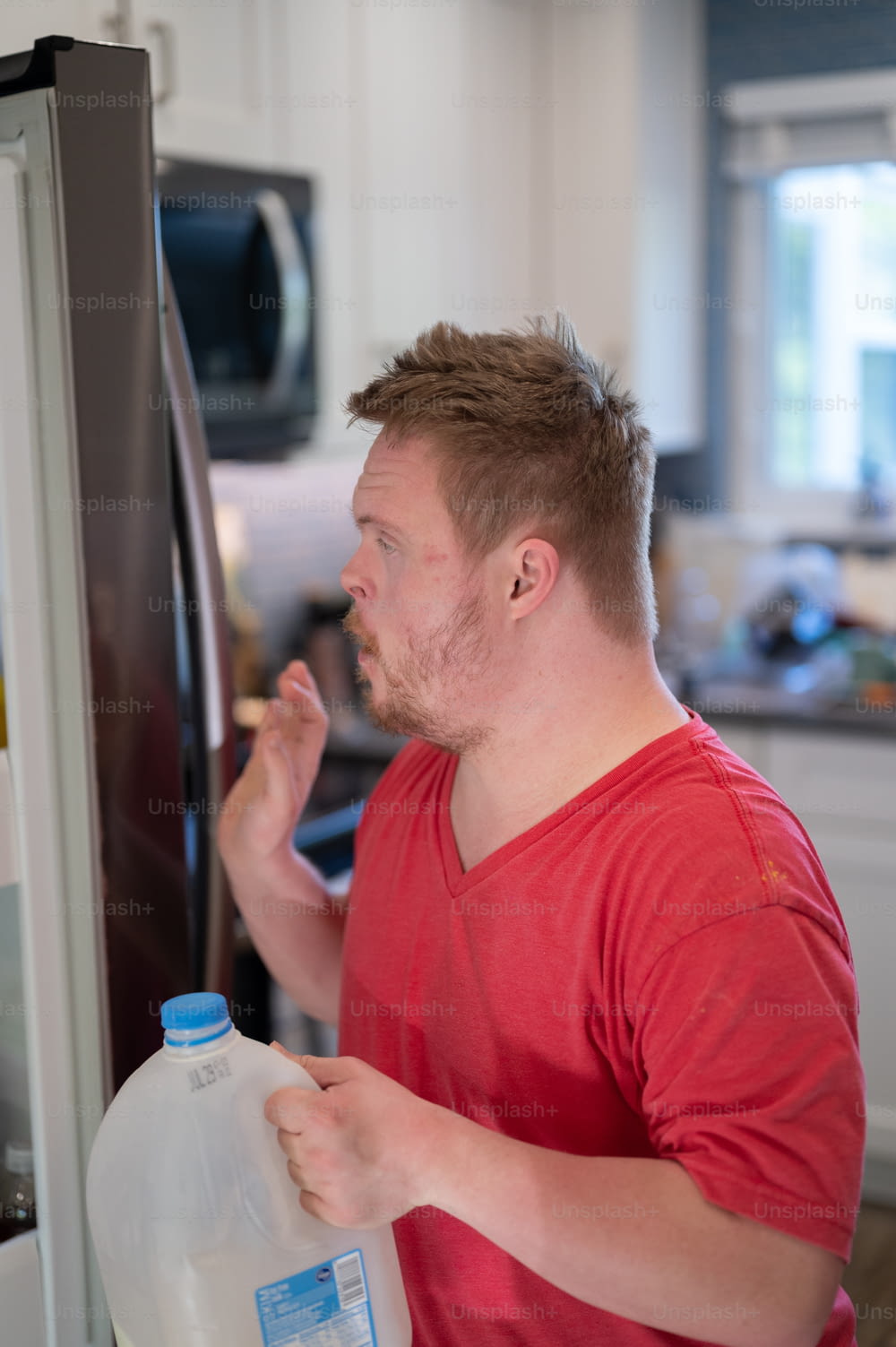 Un uomo in piedi davanti a un frigorifero con in mano una brocca di latte