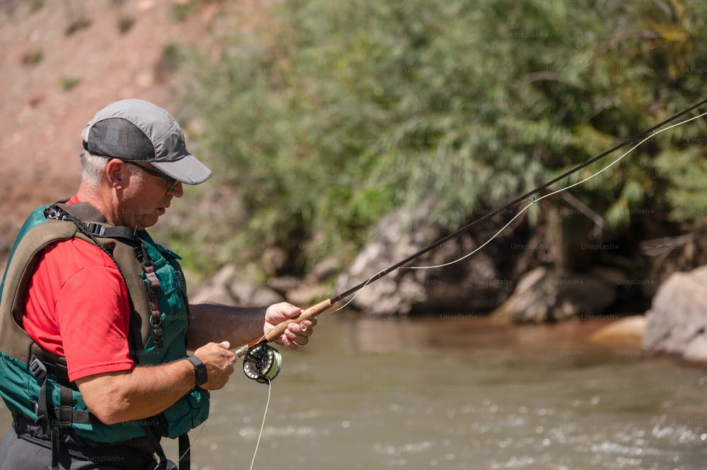 Un homme tenant une canne à pêche debout dans une rivière