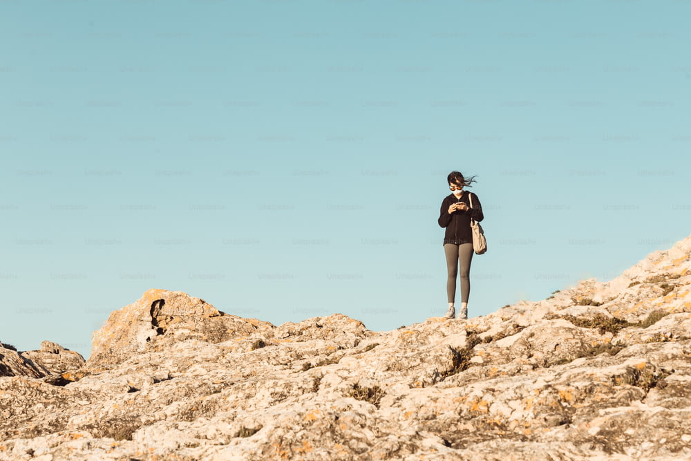a woman standing on top of a rocky hill
