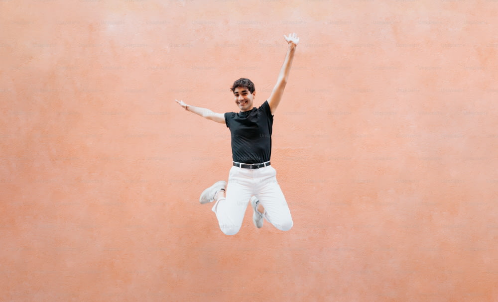 Ein Mann in schwarzem Hemd und weißer Hose springt in die Luft