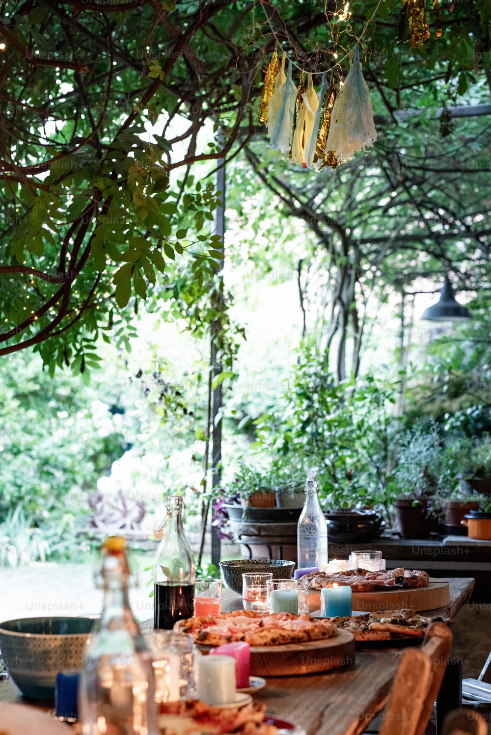 un tavolo di legno sormontato da piatti di cibo sotto un albero