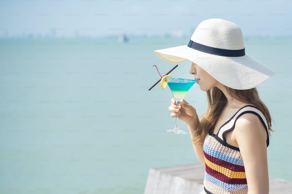 Beautiful woman is drinking ice summer drink in the beach, summer concept
