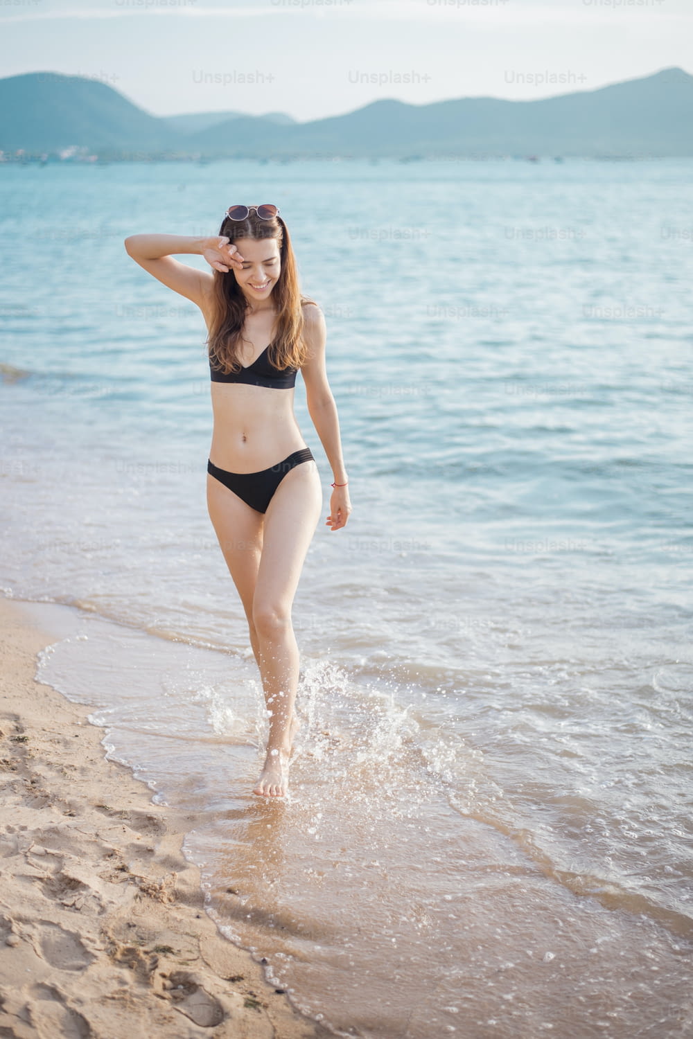 Beautiful woman in black bikini is walking from sea, summer concept