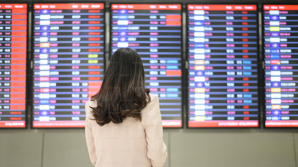 Una donna d'affari indossa una maschera protettiva nell'aeroporto internazionale, viaggia sotto la pandemia di Covid-19, viaggi di sicurezza, protocollo di distanziamento sociale, nuovo concetto di viaggio normale.
