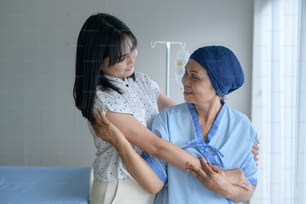 Femme patiente atteinte d’un cancer portant un foulard et sa fille de soutien dans le concept d’hôpital, de santé et d’assurance.