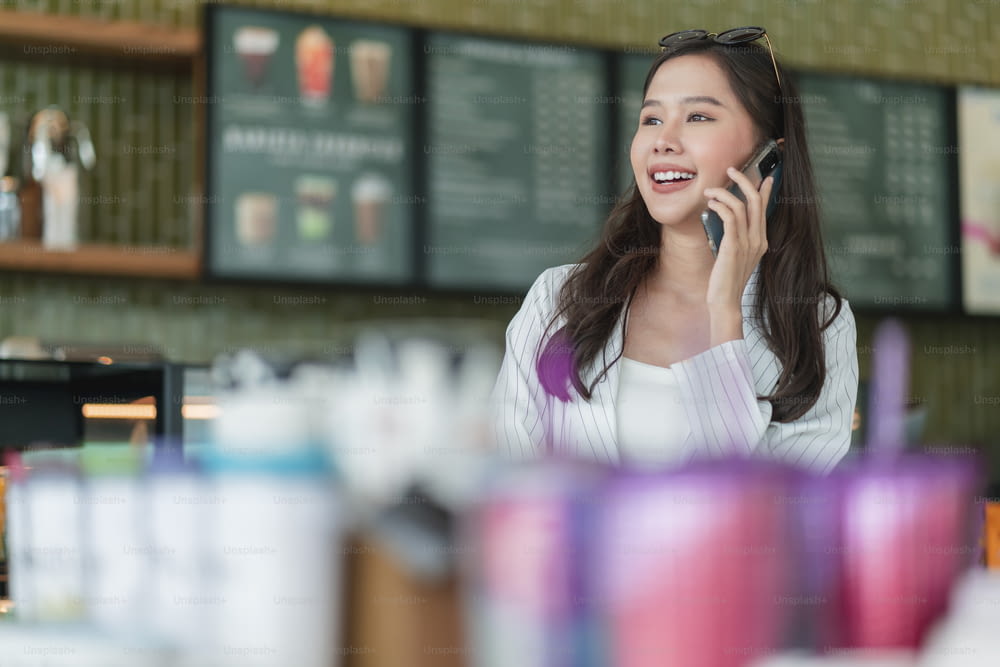 atraente inteligente casual asiático mão feminina digitando bate-papo usando smartphone de telecomunicações atitude positiva sorriso no café casual, empresário empresário inteligente que trabalha com smartphone no café