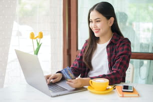 Beautiful woman is online shopping with credit card in coffee shop