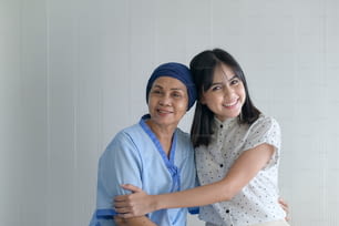Cancer patient woman wearing head scarf and her supportive daughter in hospital, health and insurance concept.