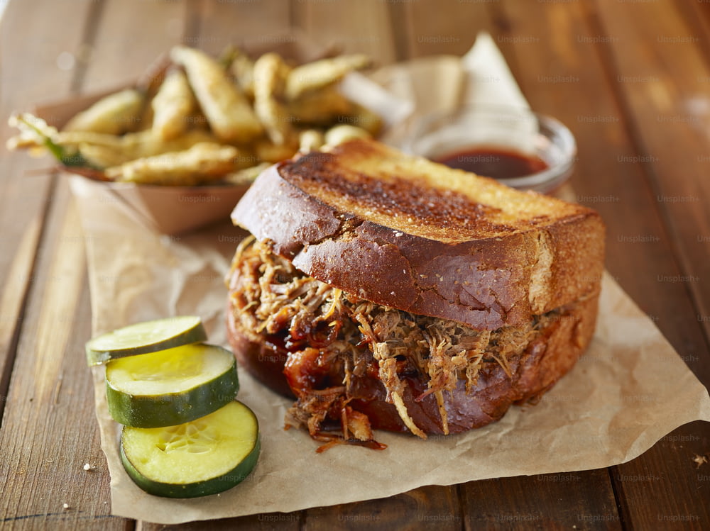 barbecue pulled pork sandwich with fried okra close up on wooden table