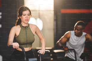Exercice de jeune femme avec des équipements de machine à vélo à la salle de fitness, entraînement à vélo actif pour un cardio et un corps sains, style de vie sportif
