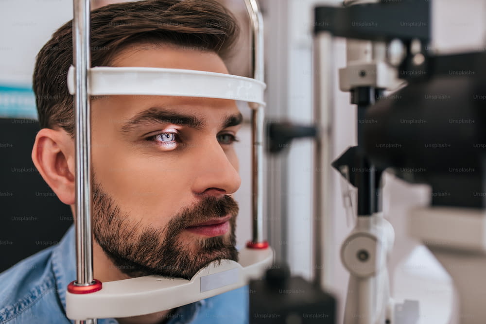 Handsome young man is checking the eye vision in modern ophthalmology clinic. Patient in ophthalmology clinic