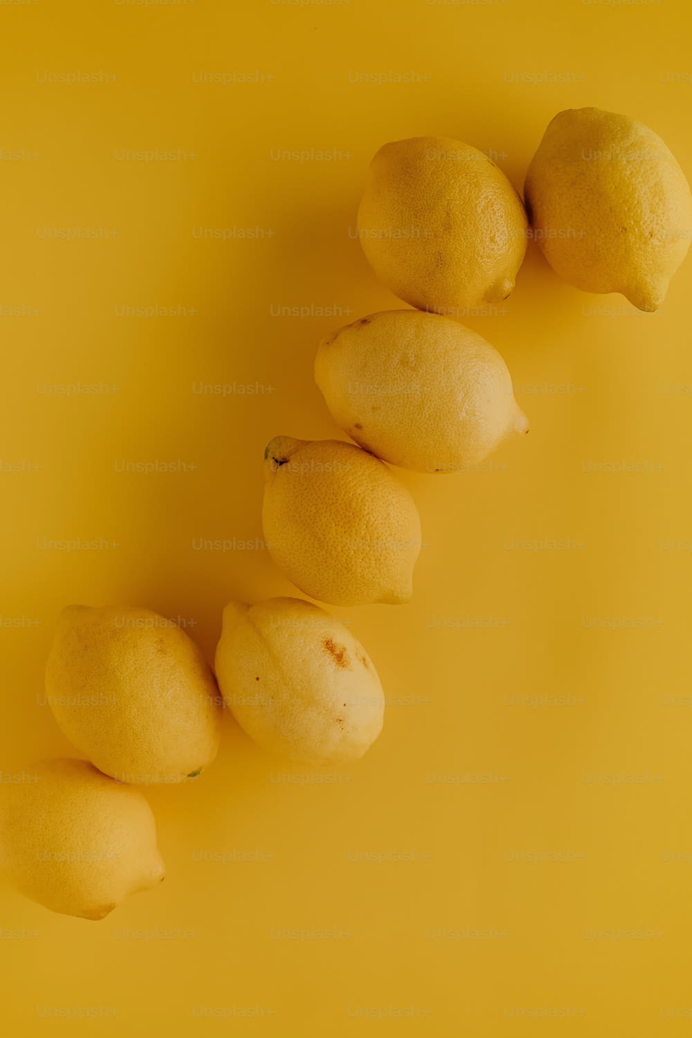 노란색 표면 위에 레몬 한 줄이 앉아 있습니다