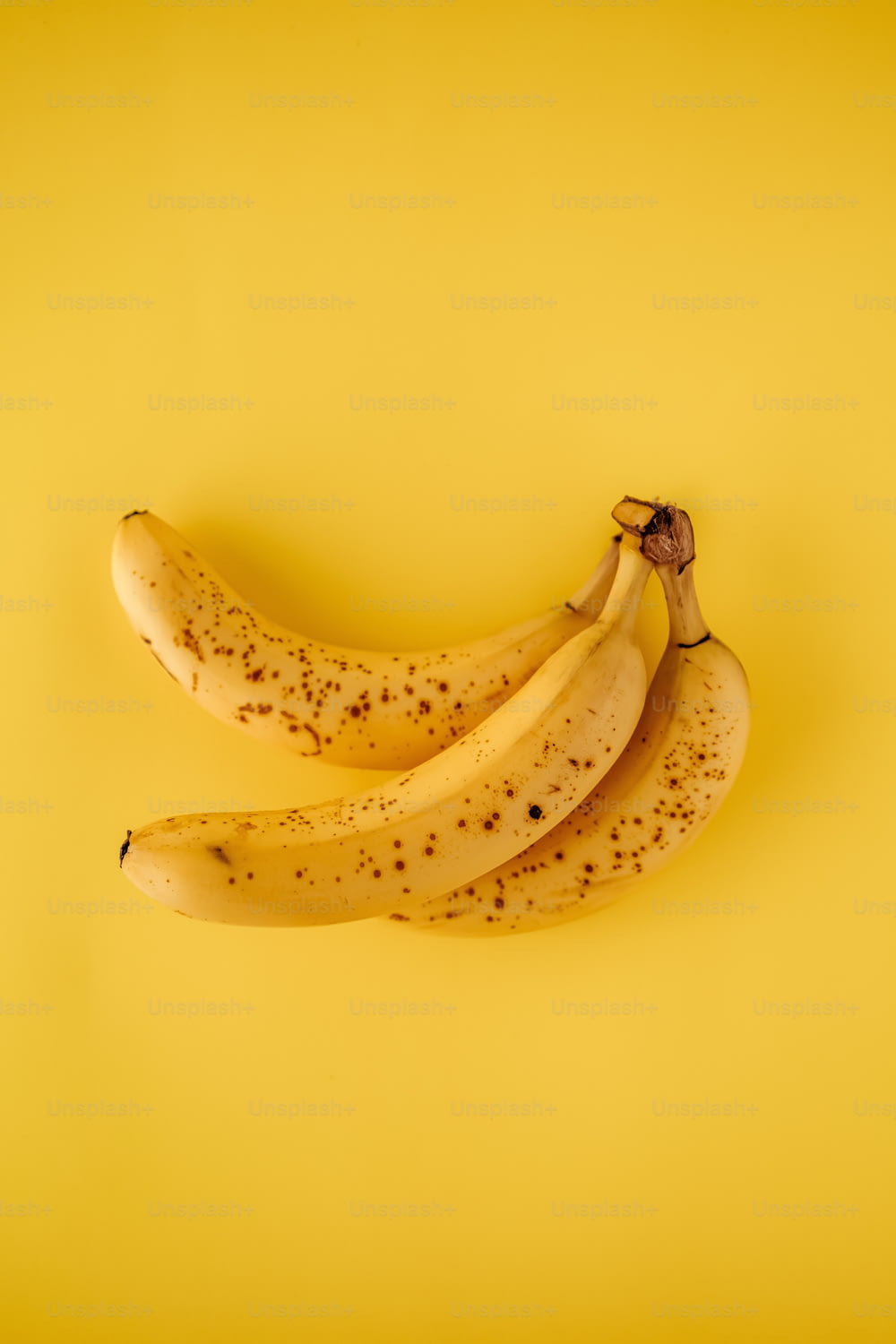 黄色の背景に3つの熟したバナナ