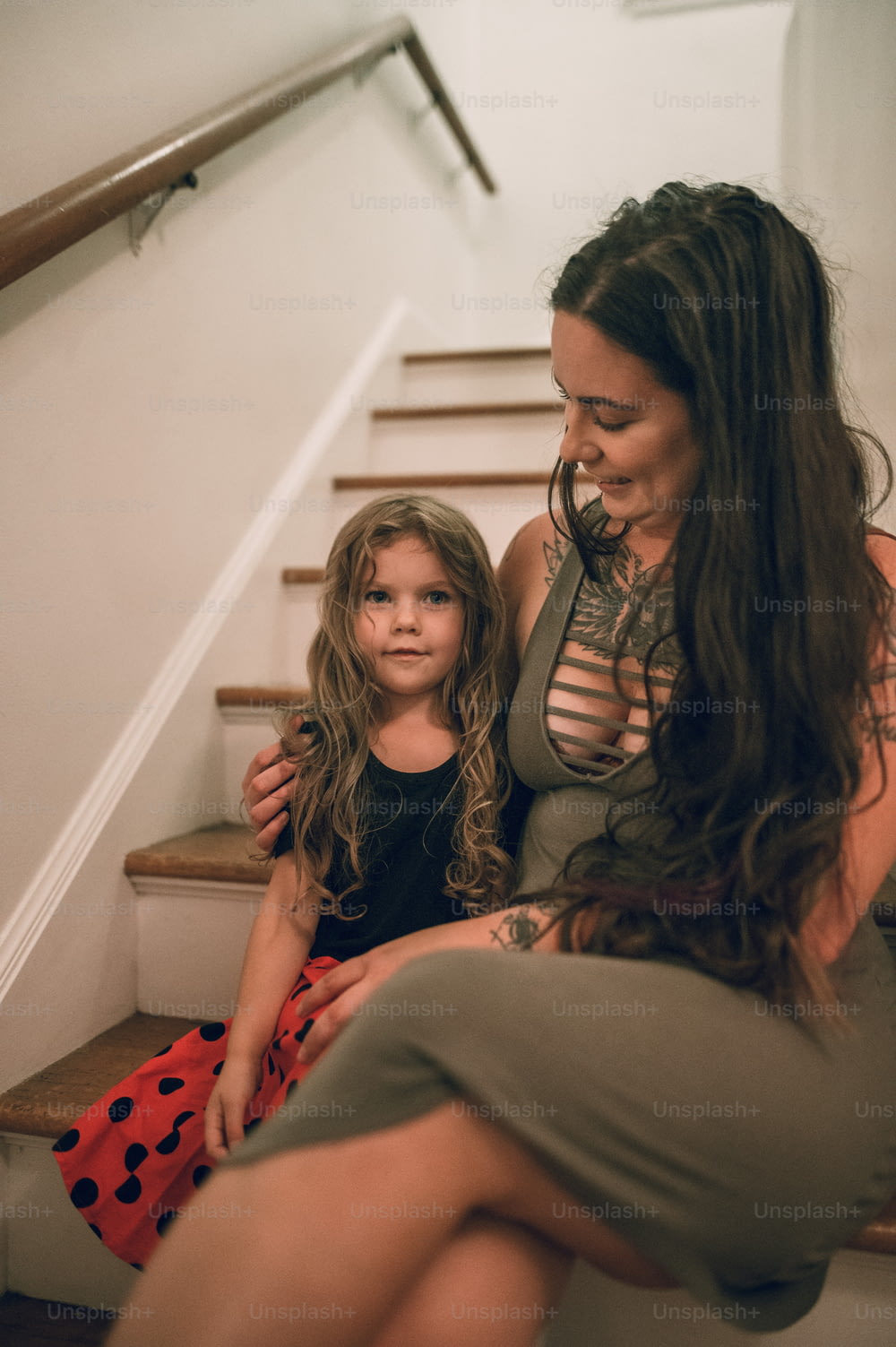 a woman sitting next to a little girl on the stairs
