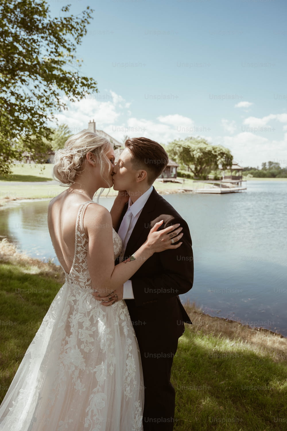 a bride and groom kissing in front of a lake